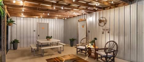 A rustic interior with a wooden ceiling, metal walls, a white door, and a table with benches.
