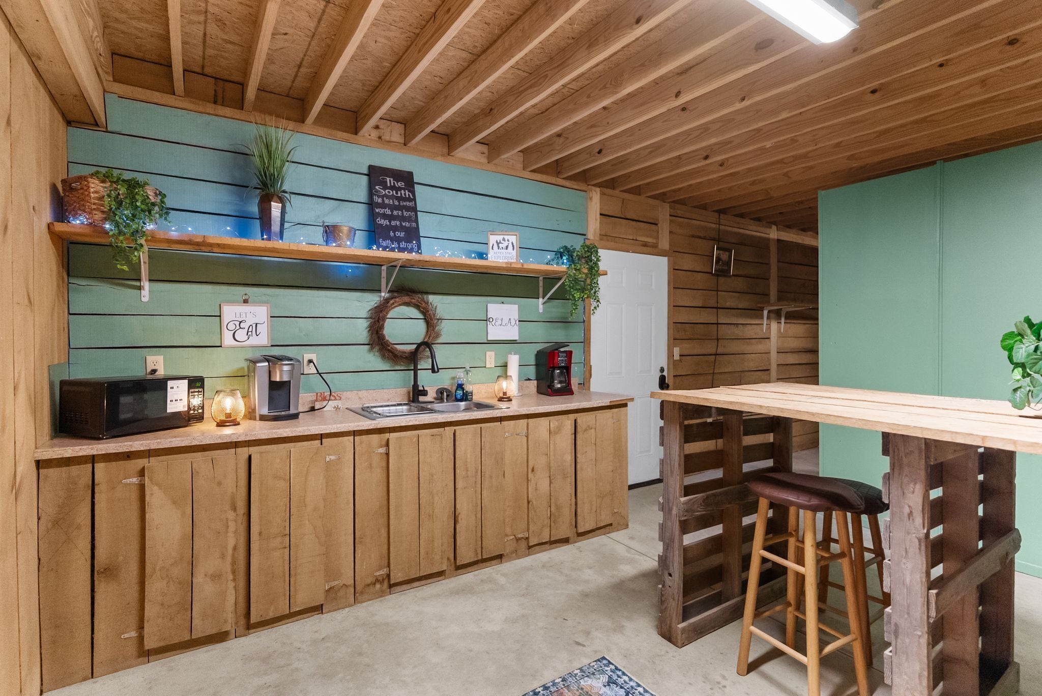 Una cocina rústica con armarios de madera, una cafetera y un refrigerador pequeño.