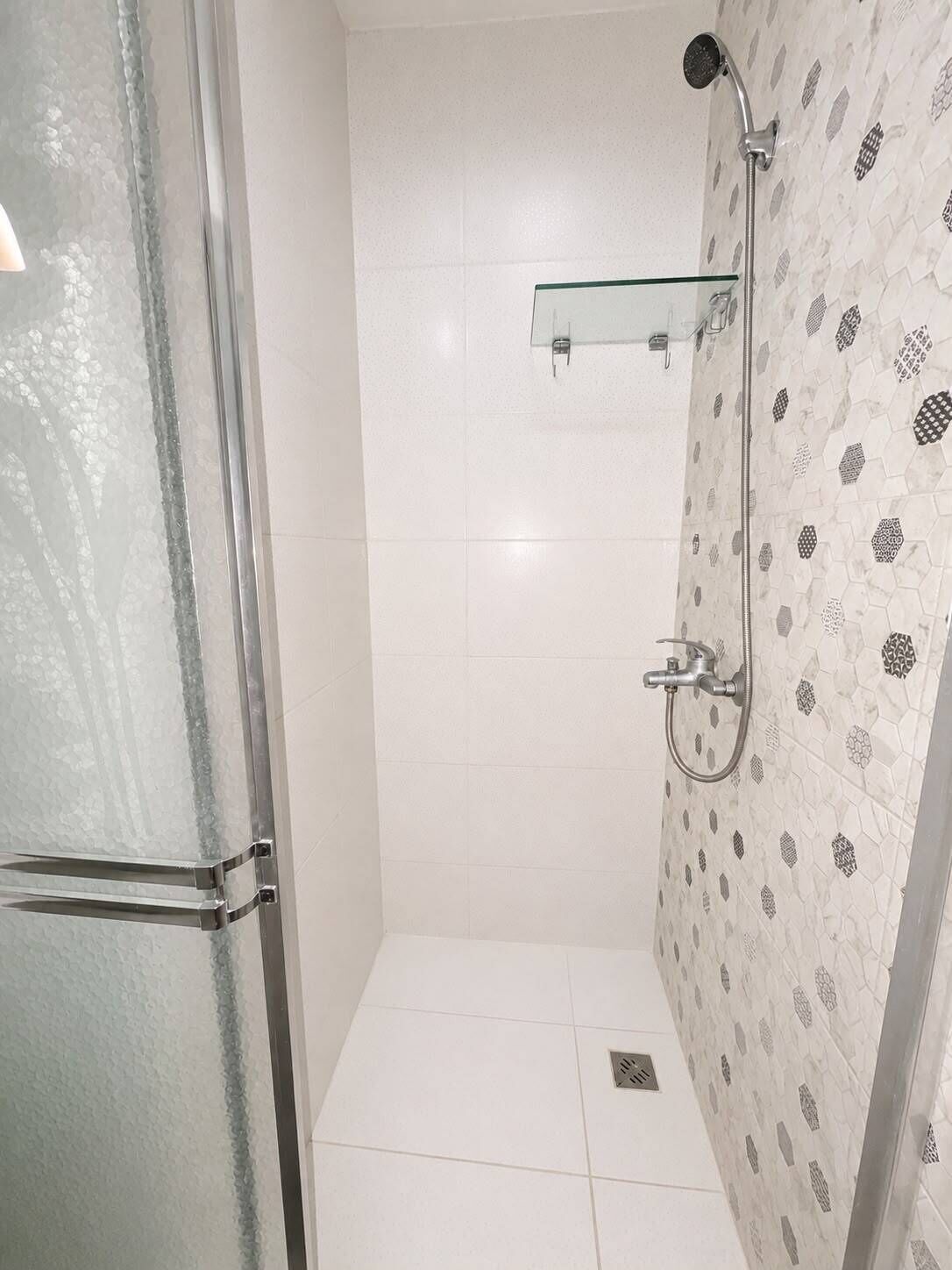 Um chuveiro com porta de vidro, um chuveiro e um porta-toalhas fixado na parede.