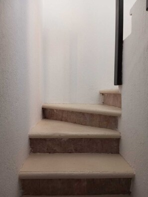 A set of beige stairs with a black handrail, leading to a higher level. - Chaánt Kay (Puerto Aventuras)