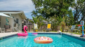 Piscina com brinquedos infláveis, uma cesta de basquete e área de estar externa.
