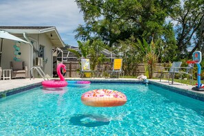 A swimming pool with inflatable toys, a basketball hoop, and outdoor seating. - New Game Room, Saltwater Pool, 15 min to Beach. Grill, Corhole, Big Fenced Yard (Clearwater)