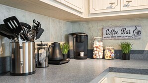 Uma cozinha com eletrodomésticos de aço inoxidável, uma cafeteira e potes com grãos de café.