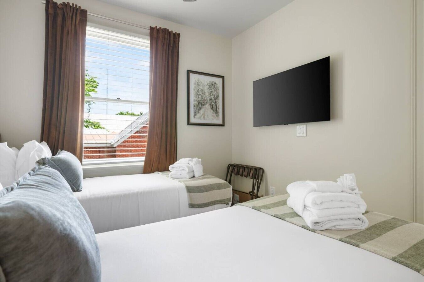 Habitación de hotel con dos camas, un televisor de pantalla plana, una ventana con cortinas y un cuadro en la pared.