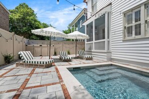 A backyard with a swimming pool, lounge chairs, and string lights. - Luxury 6BR w/ Pool Downtown CHS (Charleston)