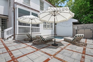 A backyard with a pool, two lounge chairs, and two umbrellas. - Luxury 6BR w/ Pool Downtown CHS (Charleston)
