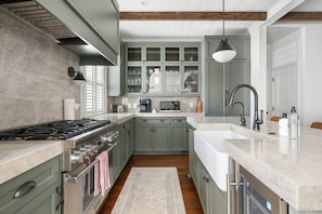 A kitchen with a gas stove, oven, and a sink with a modern faucet. - Luxury 6BR w/ Pool Downtown CHS (Charleston)