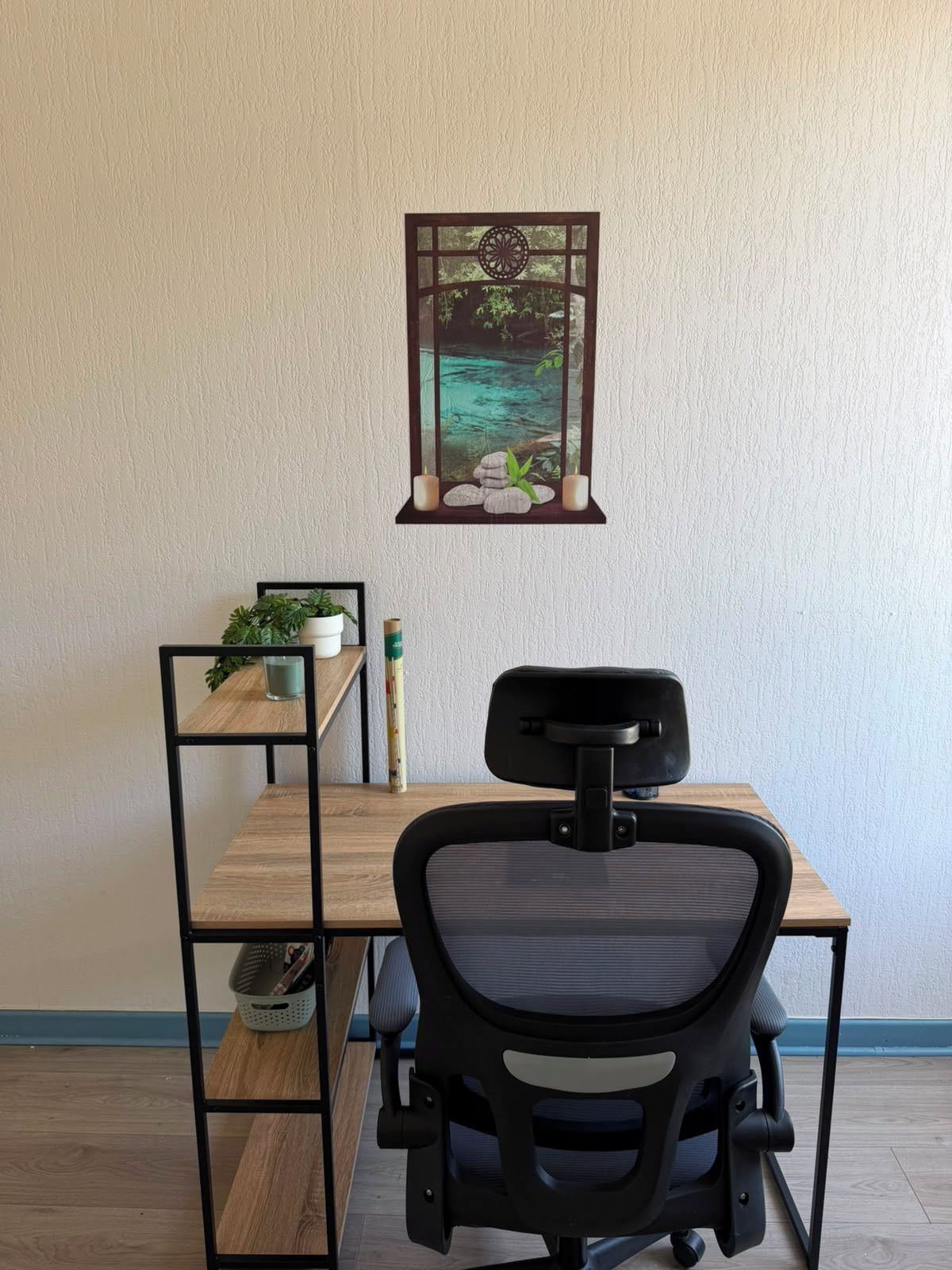 Un espace de travail comprenant un bureau, une chaise et un tableau représentant un paysage paisible, accroché au mur.