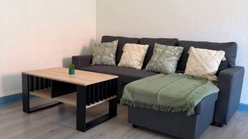 A living room with a sofa, a coffee table, and a poster on the wall.