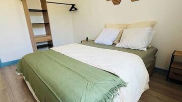 Een slaapkamer met een bed, een ladder, een kunstwerk aan de muur en een kleine plant.