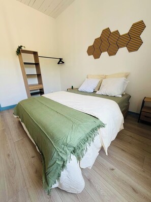Une chambre avec un lit, une échelle, une œuvre d’art murale et une petite plante.