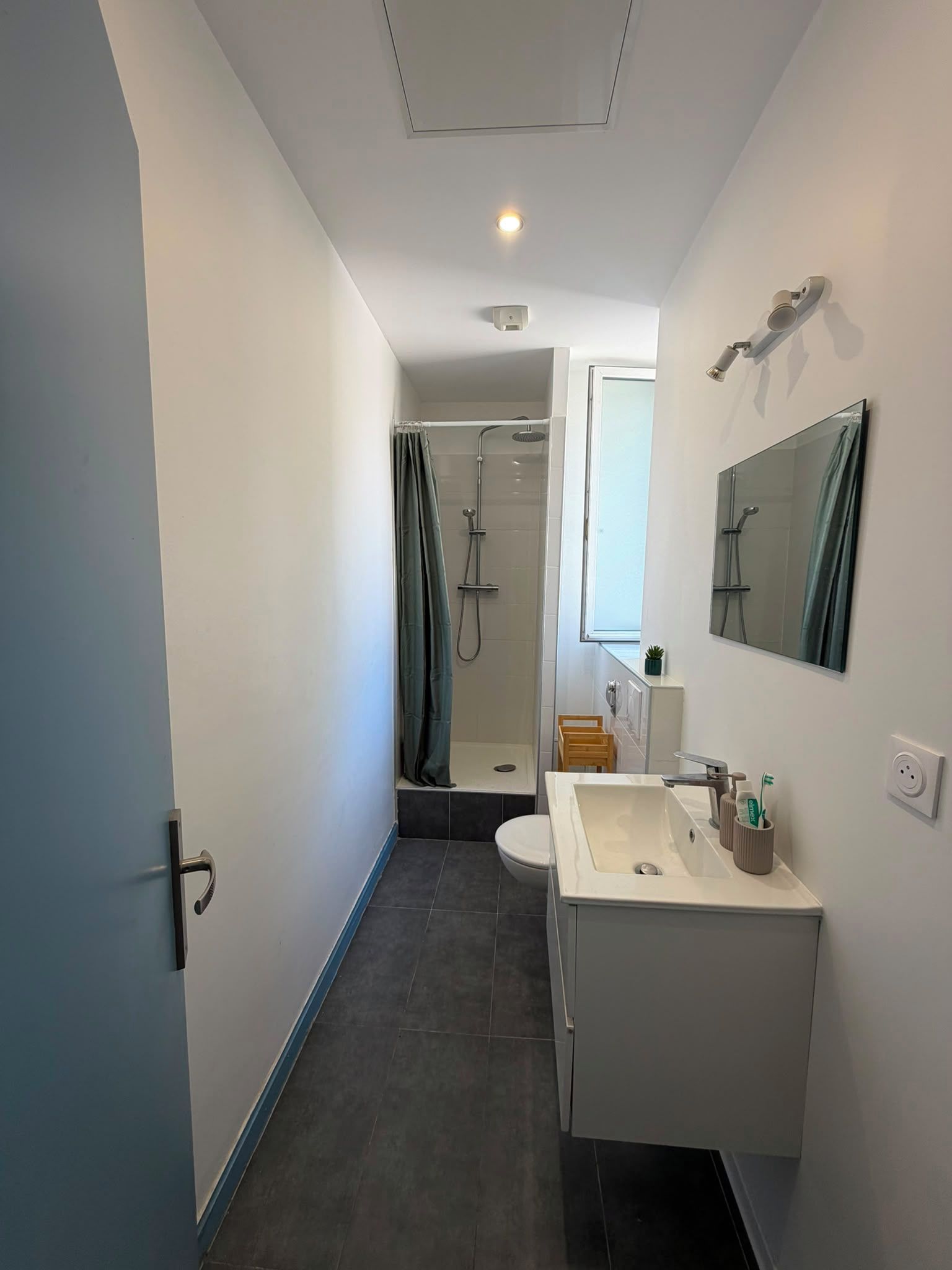 Een moderne badkamer met douche, toilet en wastafel.