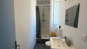 Een moderne badkamer met douche, toilet en wastafel.