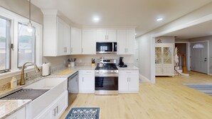 Uma cozinha moderna com armários brancos, eletrodomésticos de aço inoxidável e uma ilha central.