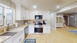 Una cocina moderna con armarios blancos, electrodomésticos de acero inoxidable y una isla central.