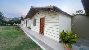 A single-story building with a thatched roof, a wooden door, and a small porch area. - Amar Bagh Resort Pushkar (Pushkar)