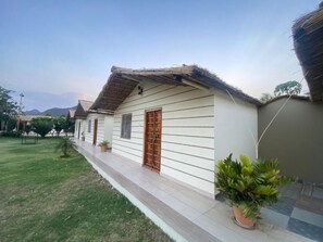 A single-story building with a thatched roof, a wooden door, and a small porch area. - Amar Bagh Resort Pushkar (Pushkar)