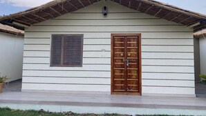 A single-story building with a thatched roof, a wooden door, and a window. - Amar Bagh Resort Pushkar (Pushkar)
