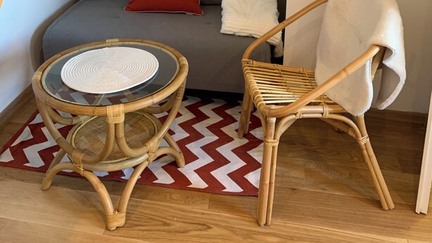A cozy room with a grey sofa, a round wicker table, a white chair, and a mirror on the wall. - A cozy little retreat on Penotte Island (Les Sables-d'Olonne)