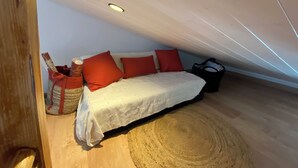 A bedroom with a bed, pillows, a bag, and a woven rug. - A cozy little retreat on Penotte Island (Les Sables-d'Olonne)