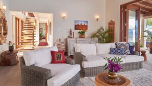A living room with a sofa set, a fireplace, and a staircase leading to another room. - Tropical-inspired 5BR Modern Seafront Villa Infinity Pool Direct Sea Access (Boscobel)
