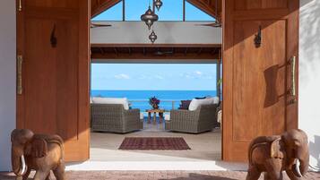 A wooden door leading to a balcony with wicker furniture and a view of the sea.