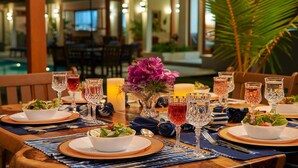 A dining table set with multiple plates, glasses, and a centerpiece of flowers. - Tropical-inspired 5BR Modern Seafront Villa Infinity Pool Direct Sea Access (Boscobel)