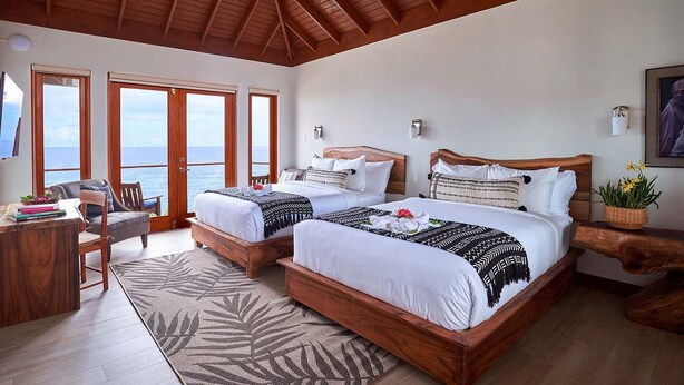 A hotel room with two beds, a desk, and a chair. There are large windows with a view of the sea. - Tropical-inspired 5BR Modern Seafront Villa Infinity Pool Direct Sea Access (Boscobel)