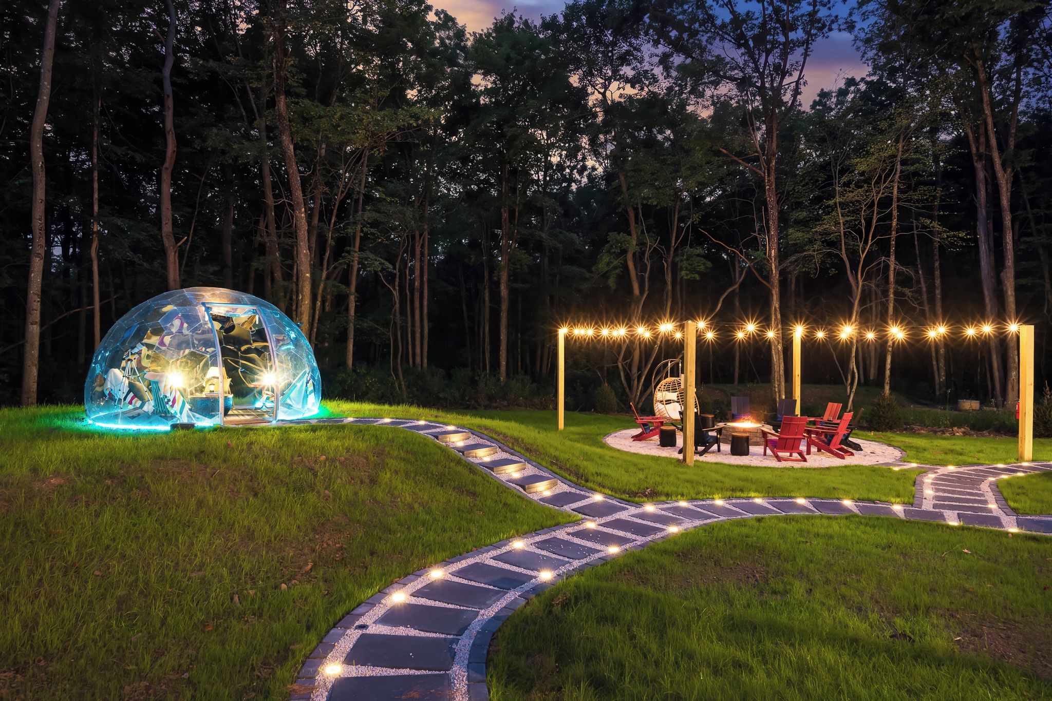 A garden with a transparent dome structure, a fire pit, and a seating area with chairs.