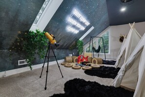 A room with a telescope, a tent, and a starry ceiling.