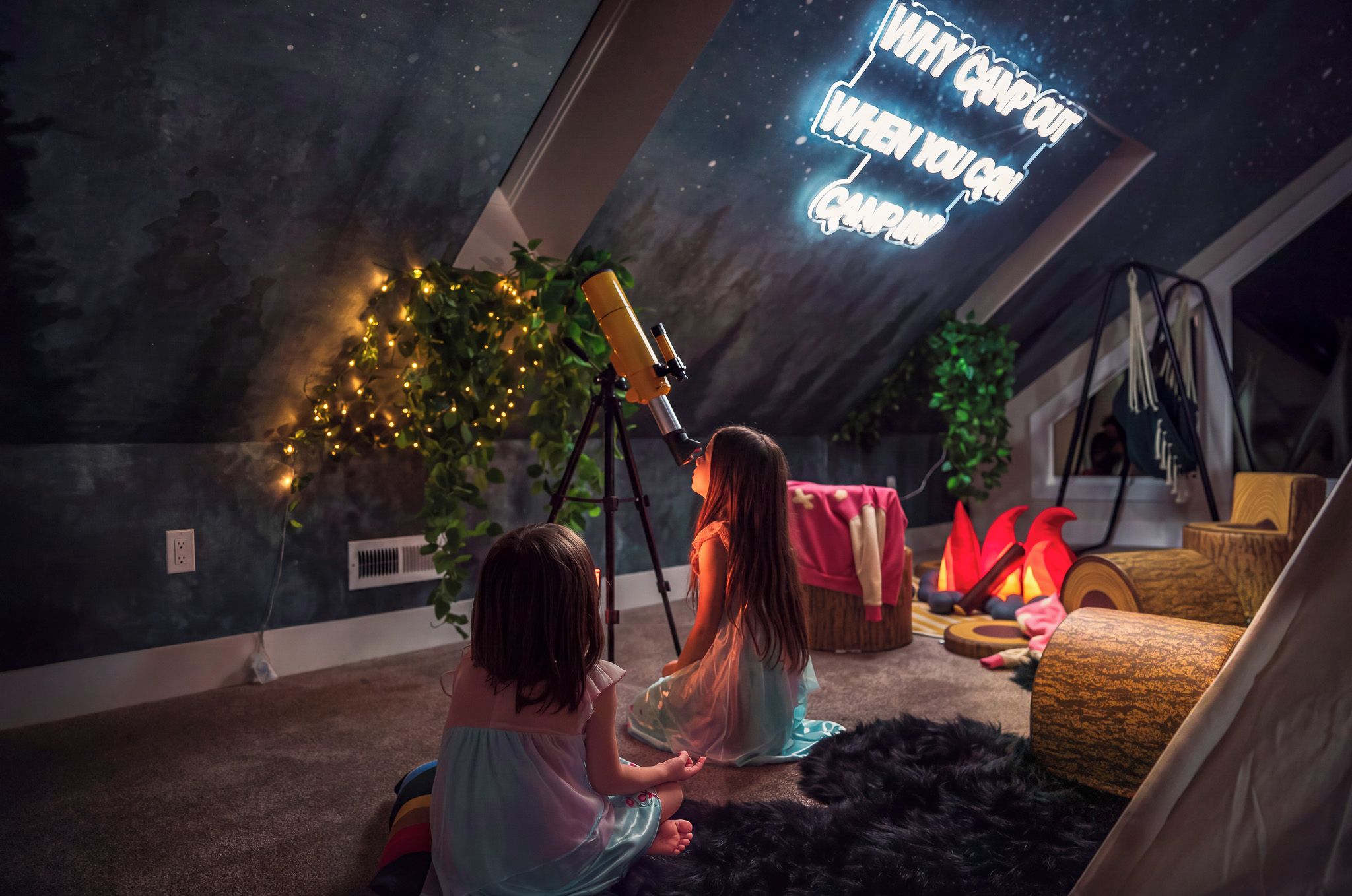 Two children observing through a telescope in a room with a starry wall mural, a cozy fireplace, and a tent-like structure.
