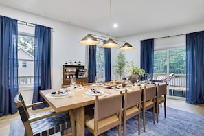 A dining area with a wooden table set for six, surrounded by wicker chairs.