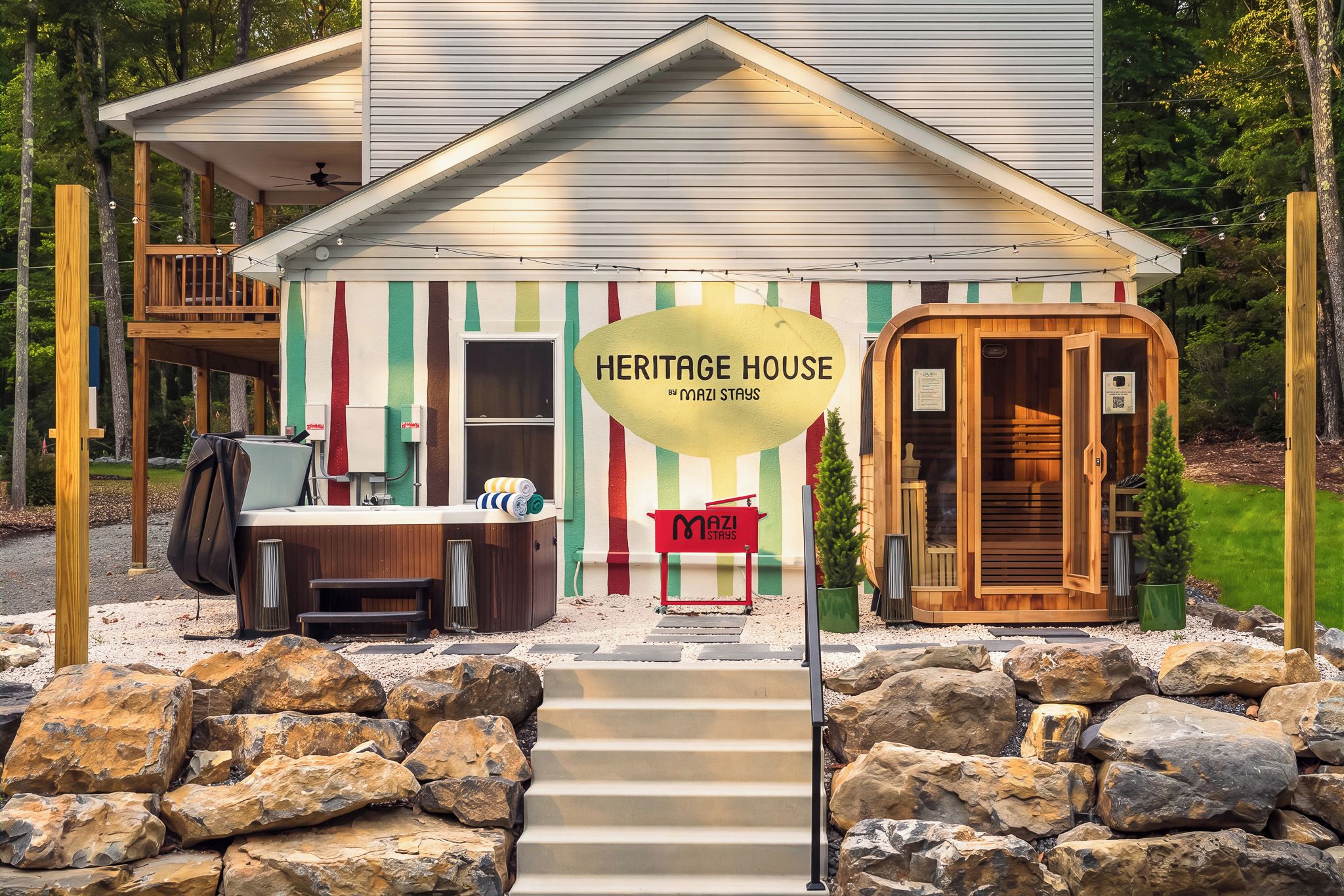 A heritage house with a wooden deck, a sauna, and a sign indicating it's by Mazi Stays.