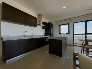 A modern kitchen with dark cabinetry, a granite countertop, and a built-in stove. - Spectacular Oceanview Escape in Torre 5 | Minutes to Centro! (Mazatlan)