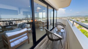 A balcony with a sofa, chairs, and a table, overlooking a cityscape. - Spectacular Oceanview Escape in Torre 5 | Minutes to Centro! (Mazatlan)