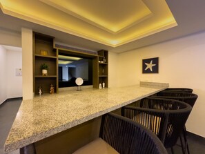 A modern kitchen with a granite countertop, black wicker chairs, and a starfish decoration on the wall. - Spectacular Oceanview Escape in Torre 5 | Minutes to Centro! (Mazatlan)