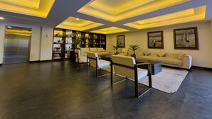 A modern living room with a dark floor, a sofa, two armchairs, a coffee table, and a bookshelf. - Spectacular Oceanview Escape in Torre 5 | Minutes to Centro! (Mazatlan)