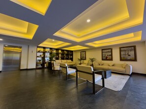A modern living room with a dark floor, a sofa, two armchairs, a coffee table, and a bookshelf. - Spectacular Oceanview Escape in Torre 5 | Minutes to Centro! (Mazatlan)