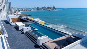 A rooftop pool with a city view, including a beach and high-rise buildings. - Spectacular Oceanview Escape in Torre 5 | Minutes to Centro! (Mazatlan)