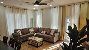 Una sala de estar con un sofá modular, una mesa de centro y un comedor con sillas.