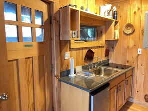 A kitchen with wooden cabinets, a stainless steel sink, and a dish drying rack. - Lakefront 4-bedroom property with spectacular views of Blue Mountain Lake. (Blue Mountain Lake)