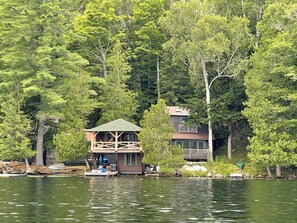 Una cabaña con un muelle, rodeada de un bosque frondoso.