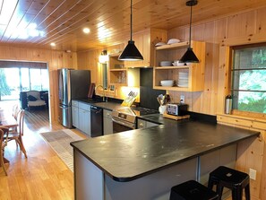 A wooden interior with a kitchen area featuring a refrigerator, stove, and sink.