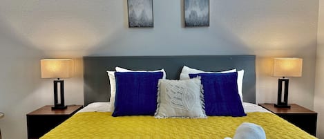 Habitación de hotel con una cama grande, dos lámparas de noche y dos cuadros en la pared.