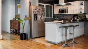 A modern kitchen with a stainless steel refrigerator, a built-in microwave, and a coffee machine. There is a wooden dining table with chairs and a potted plant. - Casa Maryna. (Villa de Cos)