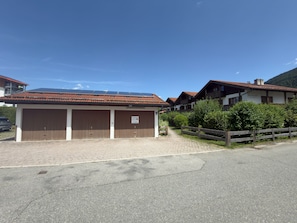 A building with a red-tiled roof, a sign indicating a no-smoking area, and a paved driveway leading to a wooden fence.