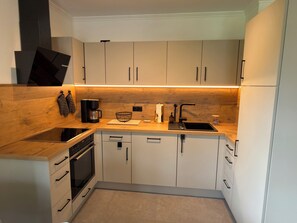 Eine kleine Küche mit Einbauofen, Kaffeemaschine und Spüle.