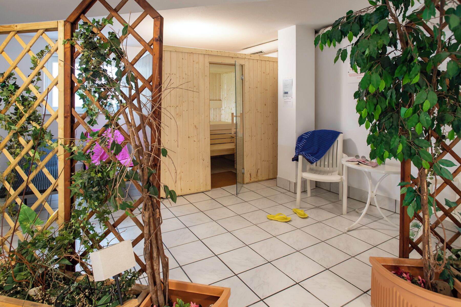 Ein Zimmer mit Holztür, weißem Stuhl und einer Topfpflanze.