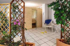 Ein Zimmer mit Holztür, weißem Stuhl und einer Topfpflanze.