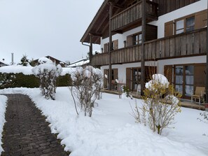 A multi-story building with a covered outdoor area and a snow-covered pathway.
